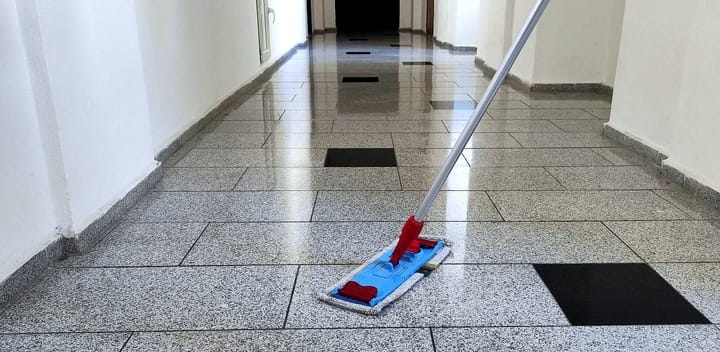 Mytí dlažby na chodbě bytového domu plochým mopem
